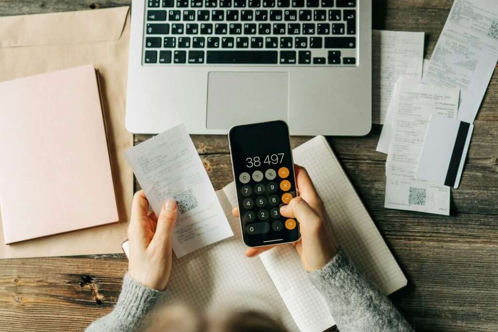 Close-up of a woman counting bookkeeping on a calculator on a phone screen.